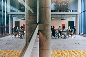 Image showing A diverse group of young business entrepreneurs gathered in a circle for a meeting, discussing corporate challenges and innovative solutions within the modern confines of a large corporation