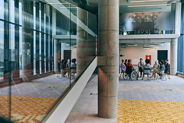 Image showing A diverse group of young business entrepreneurs gathered in a circle for a meeting, discussing corporate challenges and innovative solutions within the modern confines of a large corporation