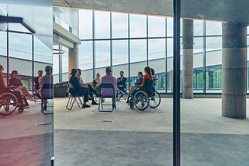 Image showing A diverse group of young business entrepreneurs gathered in a circle for a meeting, discussing corporate challenges and innovative solutions within the modern confines of a large corporation