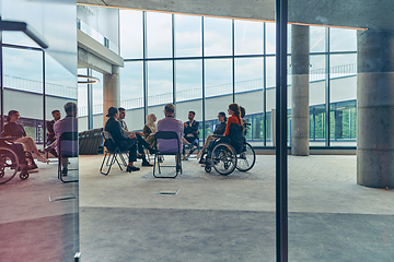 Image showing A diverse group of young business entrepreneurs gathered in a circle for a meeting, discussing corporate challenges and innovative solutions within the modern confines of a large corporation