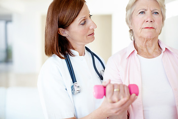 Image showing Strength and rehabilitation - Senior Health. Determined elderly female is assisted by her nurse as she lifts a dumbbell.