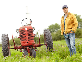 Image showing My tractor and I are in this together. Full length portrait of a farmer standing next to his tractor in a field.