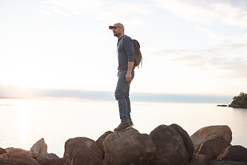 Image showing Another day, another beautiful adventure. a man wearing his backpack while out for a hike on a coastal trail.