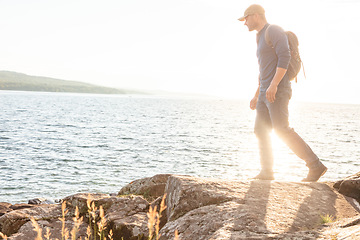 Image showing Reap the benefits nature has to offer. a man wearing his backpack while out for a hike on a coastal trail.