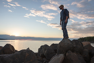 Image showing Who wouldnt want to get closer to nature. a man wearing his backpack while out for a hike on a coastal trail.