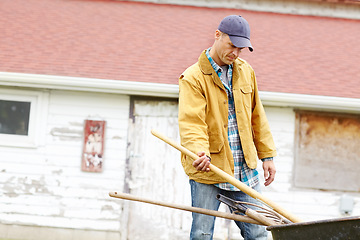 Image showing Time to start cleaning up the garden. a man taking out gardening tools from his wheelbarrow.