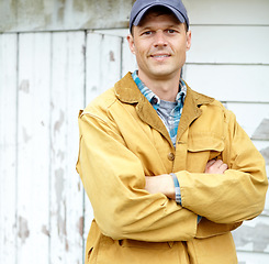 Image showing Confident and in charge. Portrait of a smiling man with his arms crossed standing outside a shed.
