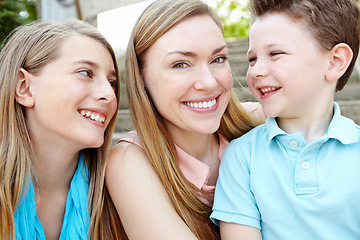 Image showing Portrait of a mother and her beautiful kids. Smiling attractive mother embracing her teen daughter and young son while outdoors.