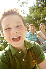 Image showing Hes always quick to laugh and smile. A happy little boy sitting outdoors with his family on a sunny day.