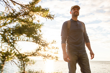 Image showing I love the feeling I get when Im hiking. a man wearing his backpack while out for a hike on a coastal trail.