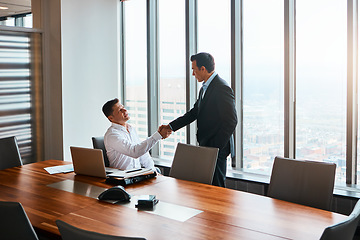 Image showing Ive been looking forward to meeting you. two businessmen shaking hands in a corporate office.