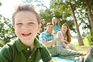 Image showing Secure in his familys love. A happy little boy sitting outdoors with his family on a sunny day.
