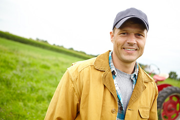 Image showing I love my job. Portrait of a smiling farmer in a field with a tractor parked behind him - Copyspace.