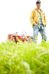 Image showing My average working day. Full length portrait of a farmer standing in a field with a tractor parked behind him - Copyspace.