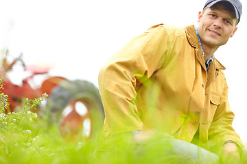 Image showing Confident in tthe results of this years harvest. Portrait of a farmer kneeling in a field with his tractor parked behind him.