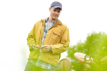 Image showing Examing the farmland. a farmer standing in a field with his tractor behind him with copyspace.