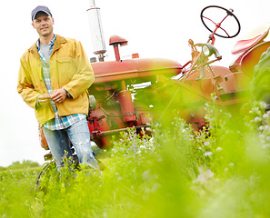 Image showing This job is my whole life. Portrait of a smiling farmer standing next to his tractor in a field.