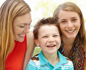 Image showing Mom told a joke. Smiling mother embracing her teen daughter and young son while outdoors.