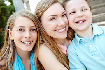 Image showing We couldnt be any closer. Smiling attractive mother embracing her teen daughter and young son while outdoors.