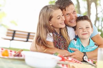 Image showing Picnic lunch with dad. Father hugging his daughter and son at the picnic table.