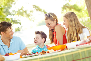 Image showing Enjoying a family meal together. A happy young family relaxing in the park and enjoying a healthy picnic.