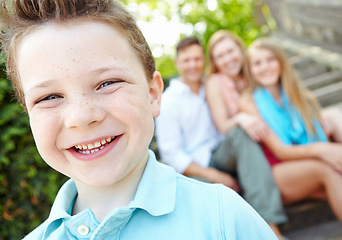 Image showing Little man of the family. Cute little boy with family sitting behind him while outdoors.