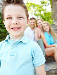 Image showing This is my family. Cute little boy with family sitting behind him while outdoors.