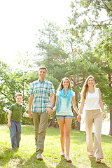 Image showing Strolling through the park. A happy young family walking through the park together on a summers day.