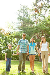 Image showing Taking a stroll together. A happy young family walking through the park together on a summers day.