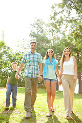 Image showing Taking a walk together. A happy young family walking through the park together on a summers day.