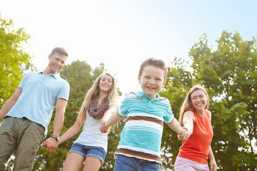 Image showing Going for a walk in the park. Low angle shot of a happy family walking hand in hand outdoors.