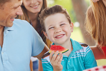 Image showing Centre of attention. Cute little boy eating watermelon with his family.