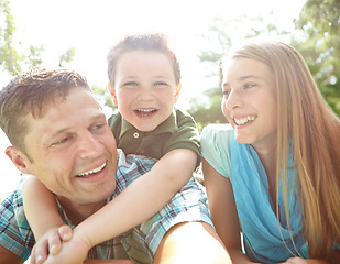 Image showing He loves his mom and dad. A happy young family lying on the ground together at the park.