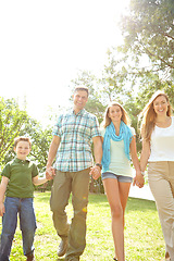 Image showing Enjoying a family stroll. A happy young family walking through the park together on a summers day.