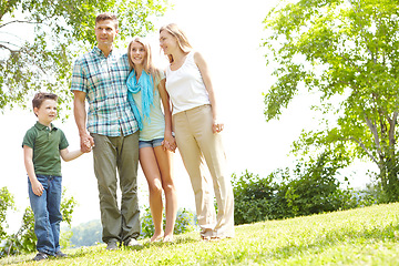 Image showing Appreciating the scenery together. A happy family standing together in the park on a summers day.