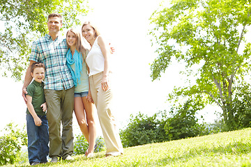 Image showing Family moments in the park. A happy family standing together in the park on a summers day.