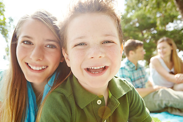 Image showing Siblings and the best of friends. A happy little boy sitting outdoors with his family on a sunny day.