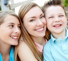 Image showing She loves her little ones. Smiling attractive mother embracing her teen daughter and young son while outdoors.