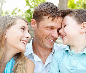 Image showing Spending time with our awesome dad. Handsome father embracing his teen daughter and young son while outdoors.