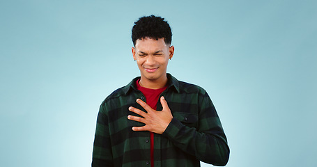 Image showing Man, hands or chest pain in studio for heart attack, emergency or cardiovascular risk. Young person, face and anxiety for asthma breathing, tuberculosis and pulmonary embolism by blue background