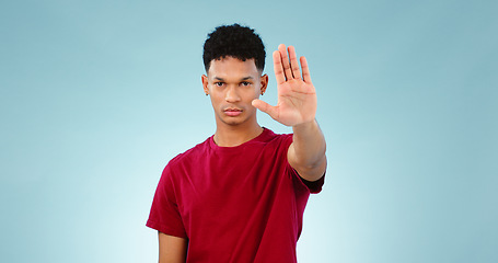 Image showing Portrait, man and hand gesture in studio for stop for warning, order or threat on blue background. Isolated model, palm or body language with attention, danger or protest for protection or safety