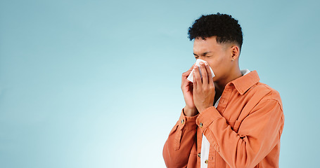 Image showing Man, blowing and nose for sinus in studio for healthcare mock up on blue background in Cape Town. Male model, hand and tissue for hay fever, flu or congestion for allergies with announcement in space