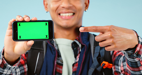 Image showing Hands, point and phone with green screen in studio for hiking app, travel mockup and space by blue background. Person, smartphone and chromakey with tracking markers, promotion and user experience