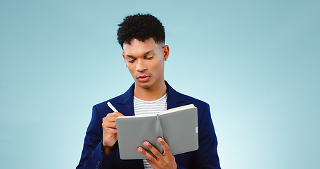 Image showing Man in studio, writing in notebook for business ideas and research for creative startup schedule. Thinking, agenda and young professional businessman with notes, pen and to do list on blue background