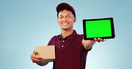Image showing Delivery person, tablet and green screen in studio for smile, mockup space and box by blue background. Courier man, cardboard package and portrait for app promotion, chromakey and tracking markers
