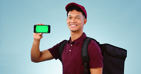 Image showing Delivery man, phone and green screen in studio with smile, mockup space and bag by blue background. Supply chain portrait, backpack and smartphone for app promotion, ecommerce and tracking markers