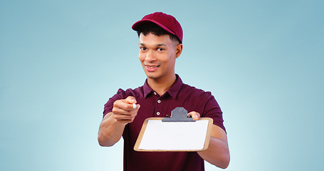 Image showing Courier man, clipboard and signature in studio portrait, smile and service with pen by blue background. African delivery guy, paperwork and document for commerce, logistics or writing in shipping job