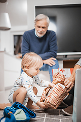 Image showing Cute little blond Caucasian toddler unpacking Christmas or Birthday present. Adorable small infant baby boy opening gift