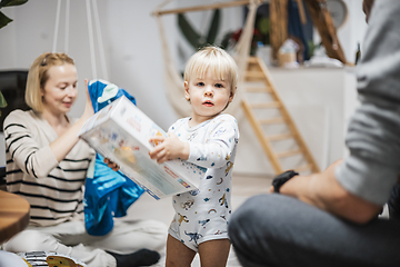 Image showing Cute little blond Caucasian toddler unpacking Christmas or Birthday present. Adorable small infant baby boy opening gift