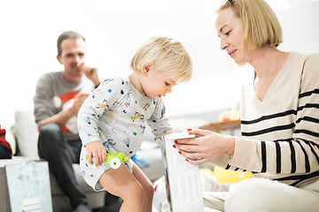 Image showing Cute little blond Caucasian toddler unpacking Christmas or Birthday present. Adorable small infant baby boy opening gift.